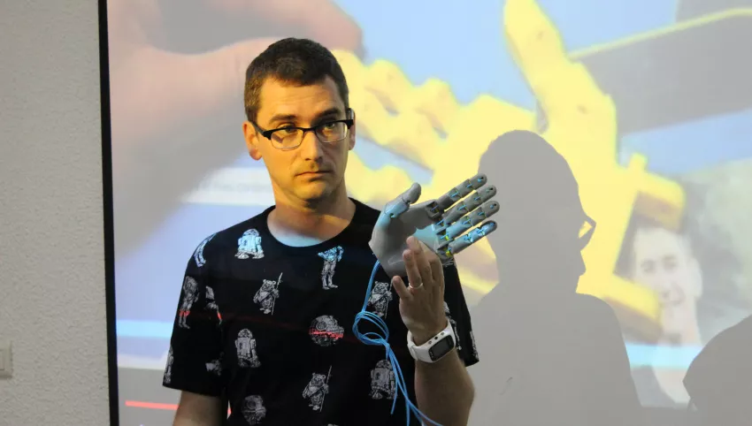 Home presentant una mà de robot en una presentacio.